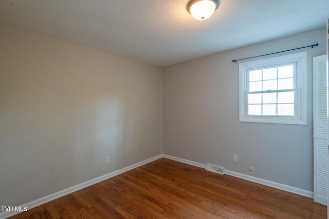 empty room with visible vents, baseboards, and wood finished floors
