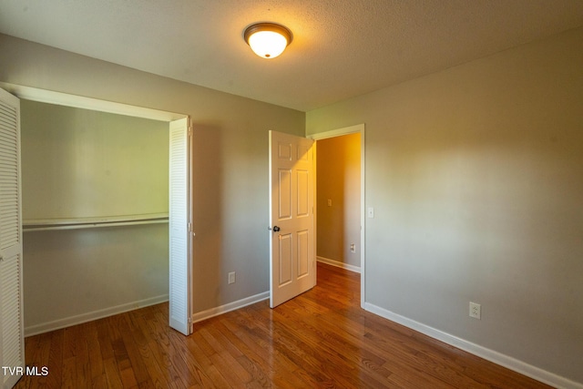 unfurnished bedroom with a closet, baseboards, and wood finished floors