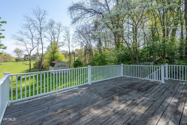 wooden terrace with an outbuilding, a storage unit, and a lawn