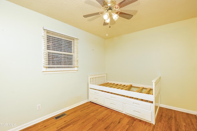 unfurnished bedroom featuring light wood finished floors, visible vents, baseboards, and ceiling fan