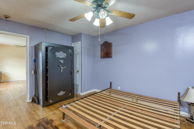 unfurnished bedroom featuring baseboards, ceiling fan, wood finished floors, and a textured ceiling