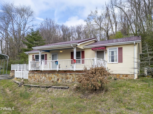 ranch-style home featuring a detached carport, metal roof, and covered porch
