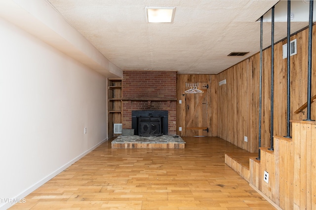 unfurnished living room featuring wood walls, visible vents, and light wood-type flooring