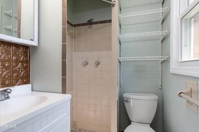 bathroom featuring toilet, tiled shower, and vanity