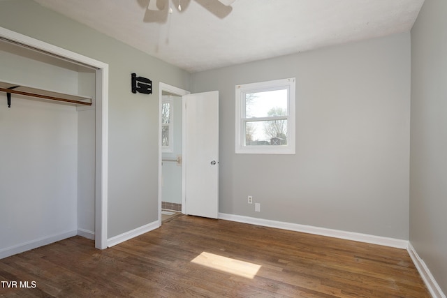 unfurnished bedroom featuring wood finished floors, a closet, a ceiling fan, and baseboards