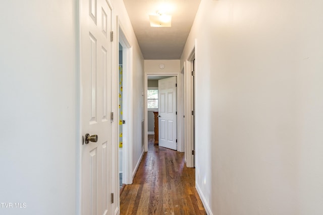corridor featuring baseboards and wood finished floors