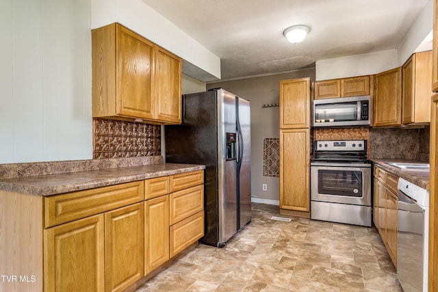 kitchen featuring decorative backsplash, dark countertops, stone finish floor, and stainless steel appliances