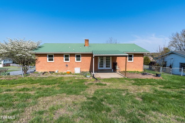 back of property with a patio, a chimney, french doors, a yard, and fence