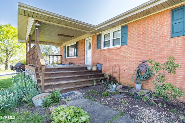 entrance to property with covered porch and brick siding