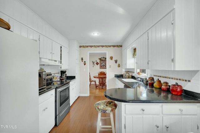 102 Delta Cir, Greeneville, TN 37743 - kitchen featuring decorative backsplash, under cabinet range hood, freestanding refrigerator, and stainless steel range with electric stovetop
