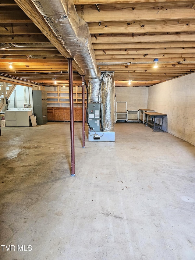unfinished basement featuring separate washer and dryer, concrete block wall, and heating unit