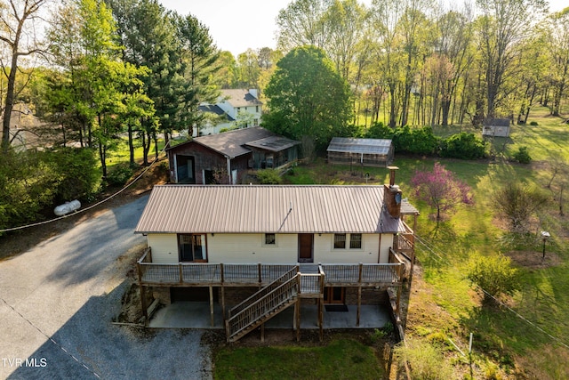 exterior space featuring a chimney, metal roof, gravel driveway, and stairs