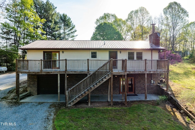back of property with a patio, driveway, stairs, a wooden deck, and metal roof