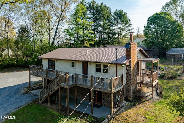 back of house featuring a chimney, metal roof, and a deck