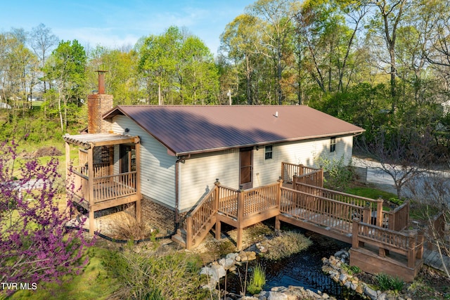 back of house featuring a wooden deck, metal roof, and a chimney