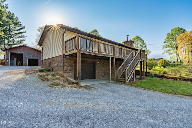 exterior space featuring an outdoor structure, a lawn, brick siding, stairs, and a deck