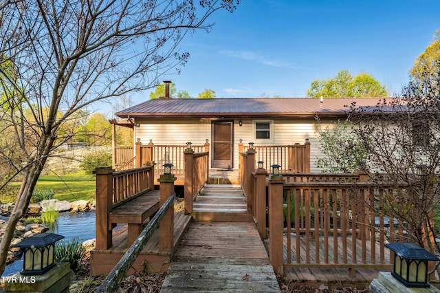 back of house featuring metal roof and a deck