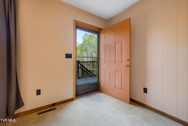 doorway to outside featuring light carpet, visible vents, and baseboards
