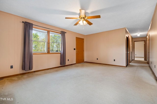 unfurnished room featuring light colored carpet, ceiling fan, and baseboards