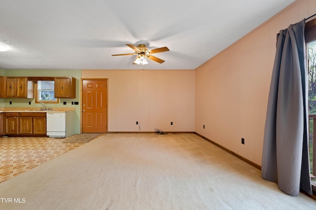 unfurnished living room featuring baseboards, light carpet, a sink, and a ceiling fan