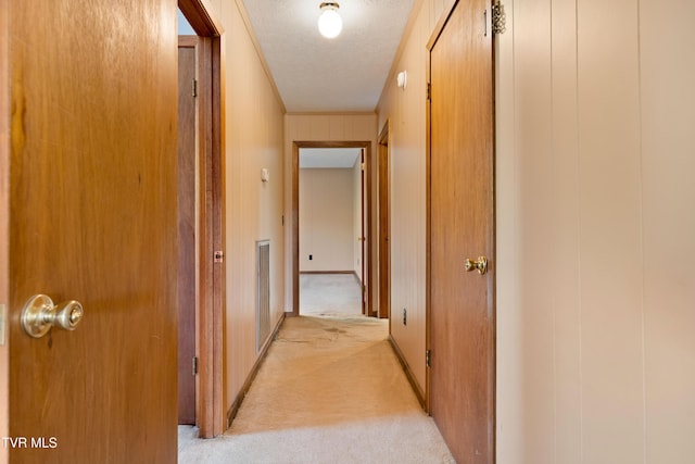hall featuring light carpet, visible vents, and a textured ceiling