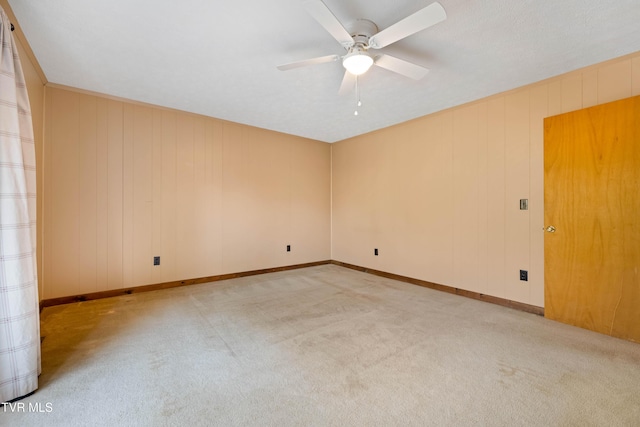 carpeted empty room with baseboards and a ceiling fan