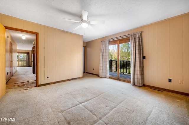 carpeted spare room with baseboards, a textured ceiling, and ceiling fan