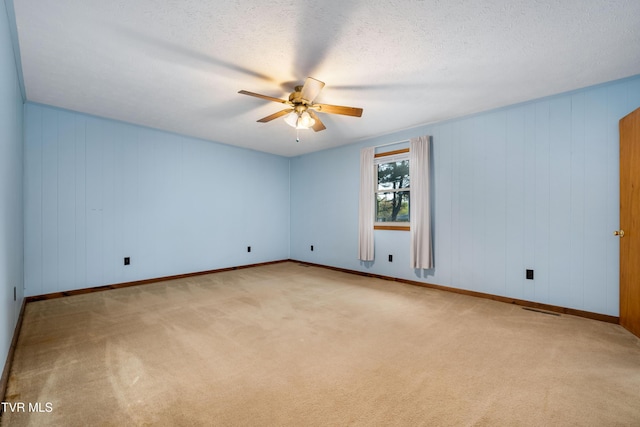 carpeted empty room with visible vents, ceiling fan, and baseboards