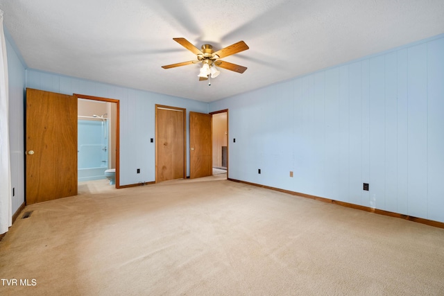 unfurnished bedroom featuring a ceiling fan, carpet flooring, baseboards, and ensuite bathroom