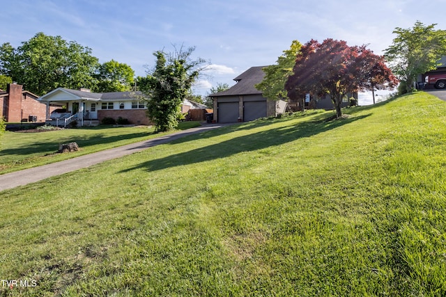 view of green lawn with driveway