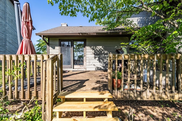 back of house with a deck, fence, and roof with shingles