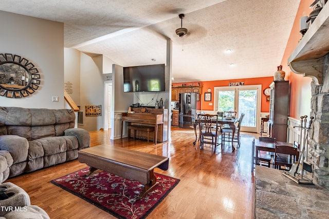 living room with a textured ceiling, light wood finished floors, and stairway