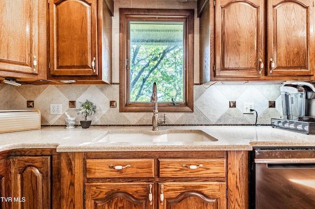kitchen with a sink, dishwashing machine, decorative backsplash, and brown cabinetry