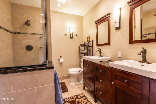 bathroom with a tile shower, toilet, double vanity, baseboards, and tile patterned floors