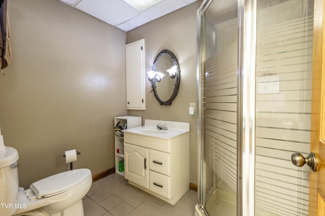 full bath featuring toilet, tile patterned flooring, a shower stall, vanity, and a drop ceiling