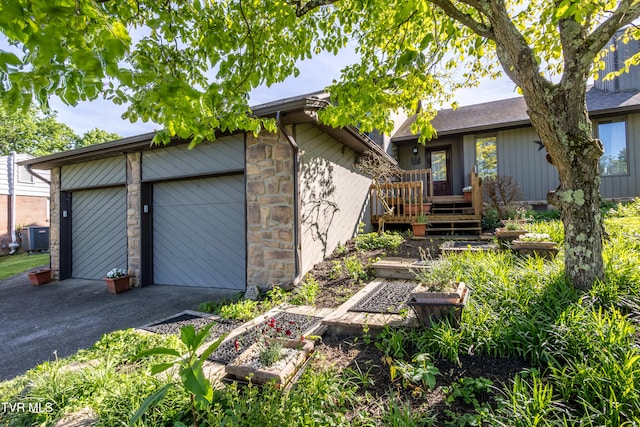 view of side of property featuring a garage, asphalt driveway, and stone siding