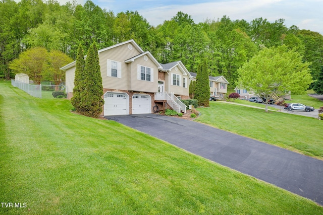 bi-level home featuring a front yard, a garage, aphalt driveway, brick siding, and fence