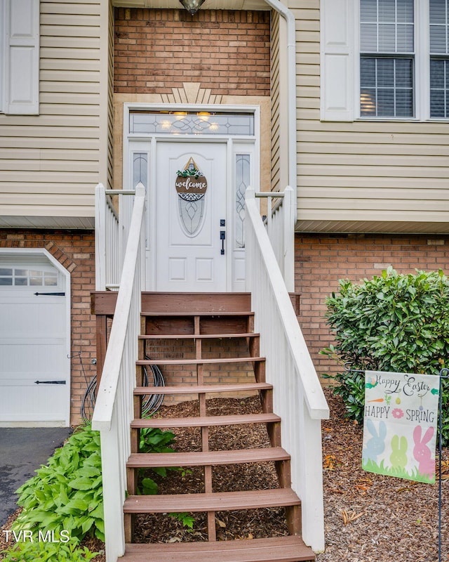 property entrance featuring a garage and brick siding