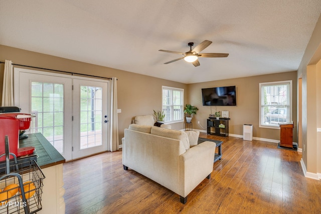 living area featuring a wealth of natural light, hardwood / wood-style floors, a ceiling fan, and baseboards