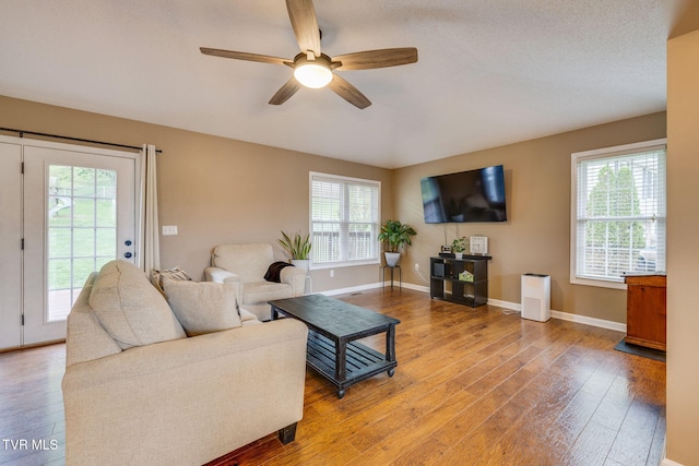 living room with ceiling fan, a wealth of natural light, wood finished floors, and baseboards