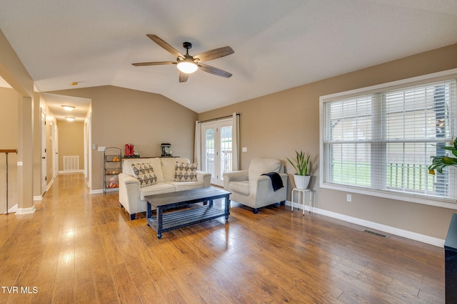 living room with a ceiling fan, visible vents, vaulted ceiling, and light wood-type flooring
