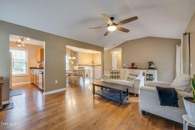 living room featuring dark wood-style flooring, baseboards, vaulted ceiling, and ceiling fan with notable chandelier