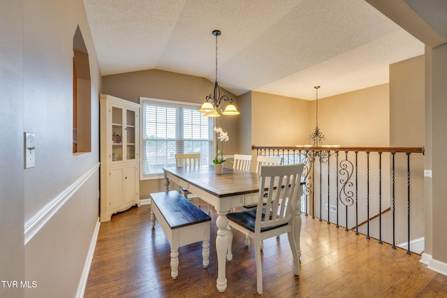 dining room with an inviting chandelier, wood finished floors, lofted ceiling, and baseboards