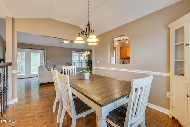 dining space with a chandelier, wood finished floors, and vaulted ceiling