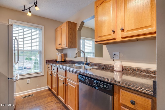 kitchen with light wood finished floors, a sink, visible vents, dishwasher, and freestanding refrigerator