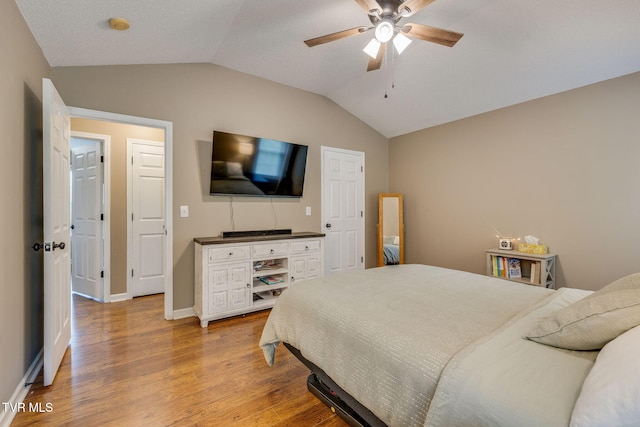 bedroom with lofted ceiling, light wood-style floors, ceiling fan, and baseboards