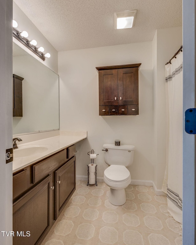 bathroom with baseboards, toilet, a textured ceiling, and vanity