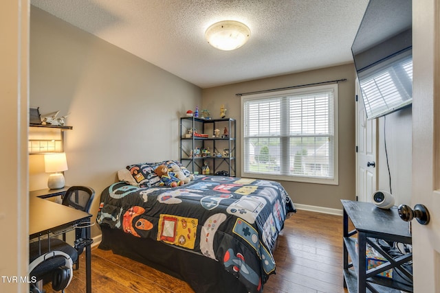bedroom with baseboards, hardwood / wood-style flooring, a textured ceiling, and multiple windows