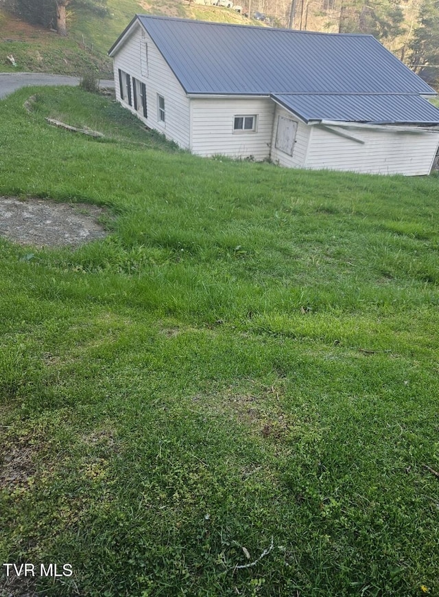 view of side of property with a yard and metal roof