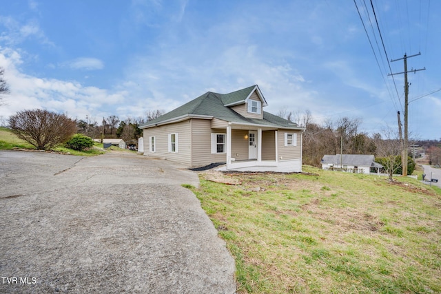 view of front of property with aphalt driveway, a porch, and a front lawn